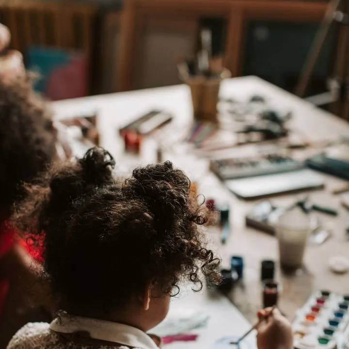 A child painting with watercolours at a well-used art table
