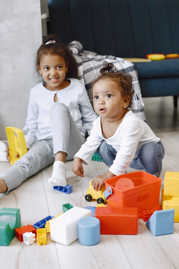 Two children playing with colourful building toys indoors