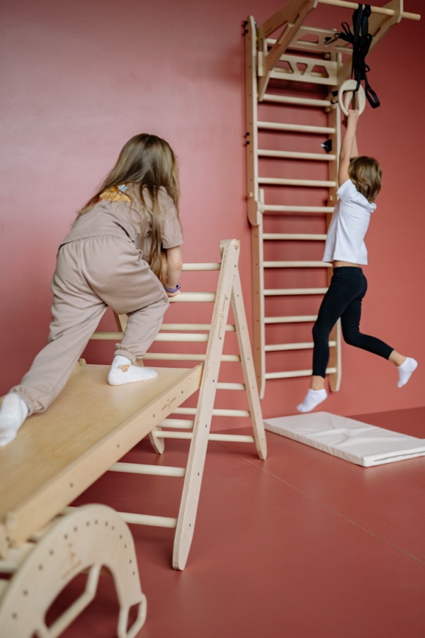 Children climbing and swinging on indoor play equipment